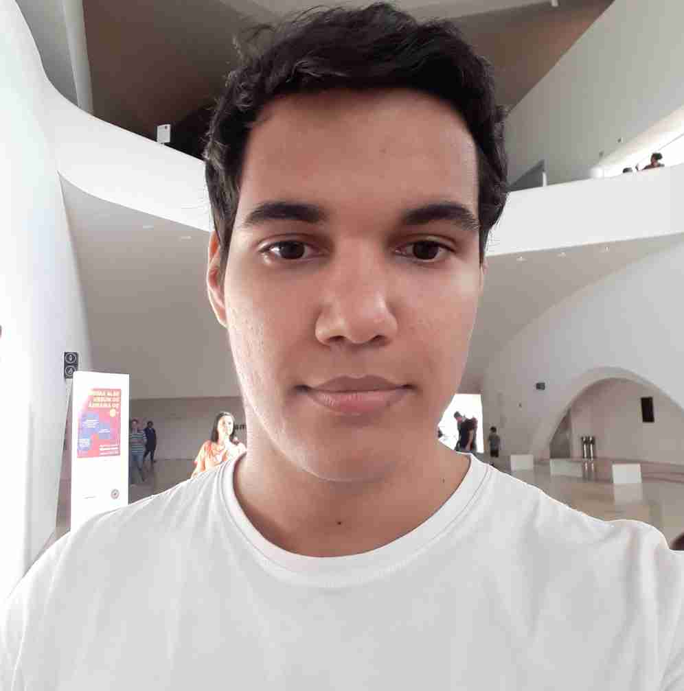 imagem de rosto de arthur rocha, usando camisa branca, cabelo preto e olhos castalhos.